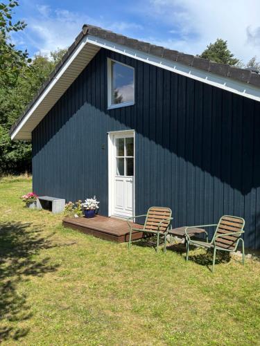 a blue house with two chairs in front of it at Moderne sommerhus i naturskønne omgivelser in Gedser