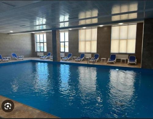 a large swimming pool with blue chairs in a building at Alvina complex Vakas Tsakghadzor apartament in Tsaghkadzor