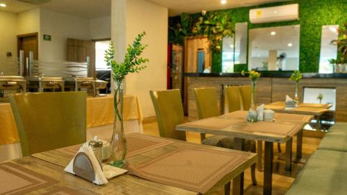 a restaurant with wooden tables and chairs with flowers on them at Hotel Oxford Barranquilla in Barranquilla
