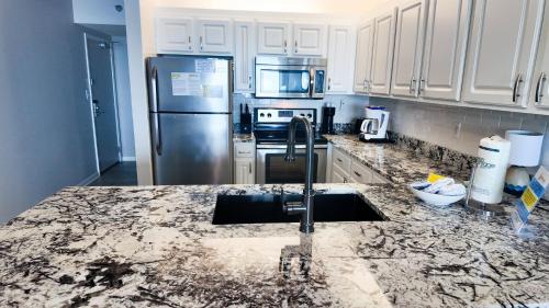 a kitchen with a sink and a stainless steel refrigerator at Stunning Views, 3BD/2BA w/ Private Balcony in Orange Beach