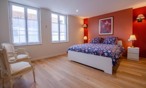 a bedroom with a bed and a chair and windows at Entre seine et vignes in Neuville-sur-Seine