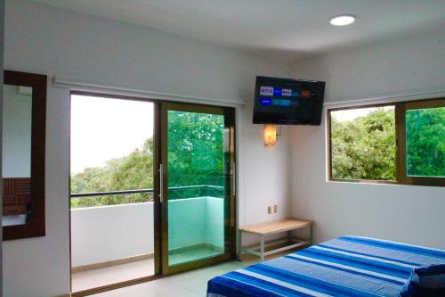 a bedroom with a bed and a tv and windows at Hotel Monkey House Tuxtla Gutiérrez in Tuxtla Gutiérrez