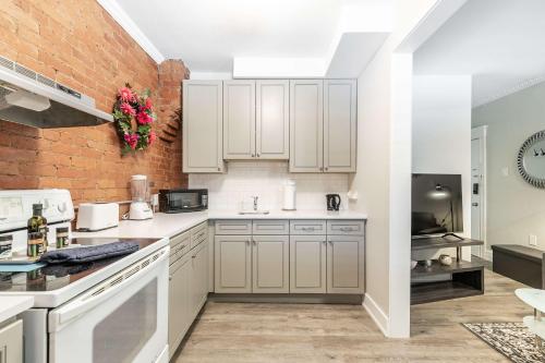 a kitchen with white cabinets and a brick wall at Boutique 2BR Apartment on James St North Sleeps 6 in Hamilton