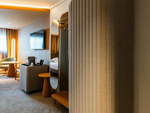 a hotel room with a bedroom and a room with a bed at Novotel Reims Tinqueux in Reims