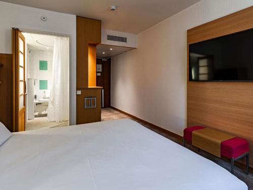 a bedroom with a large bed and a flat screen tv at Novotel Reims Tinqueux in Reims