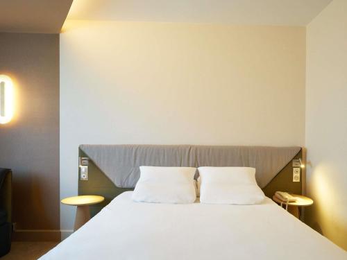 a bedroom with a large bed with two white pillows at Novotel Reims Tinqueux in Reims