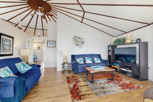 a living room with two blue couches and a tv at Neptune's Trident in Lincoln Beach