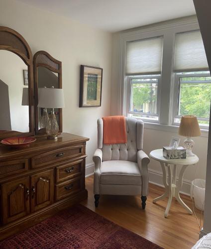 a bedroom with a chair and a dresser and a mirror at Cottage on Caledonia Bed & Breakfast in Stratford