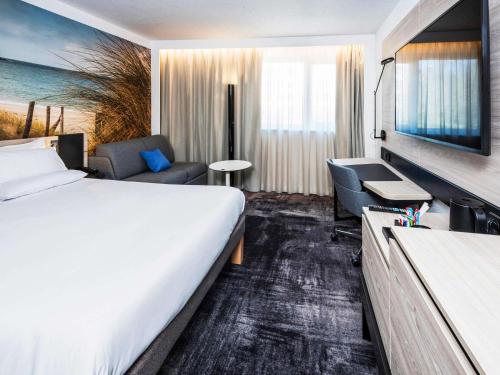 a hotel room with a large bed and a couch at Novotel Rennes Alma in Rennes