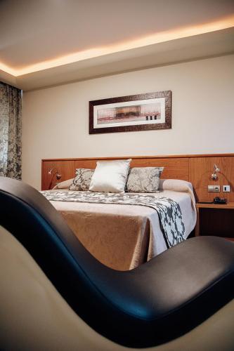 a bedroom with a bed with a chair in it at Hotel Cies in Calvarrasa de Abajo