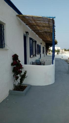 a white building with a porch with a plant at Glaros Beach in Perivolos