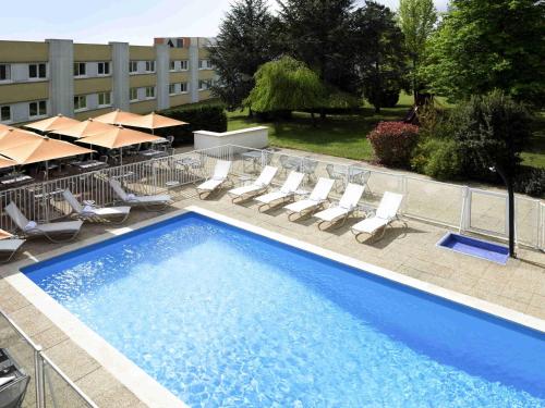 a large swimming pool with chairs and umbrellas at Novotel Macon Nord - Porte de Bourgogne in Mâcon