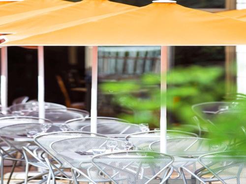 a row of empty tables with an umbrella at Novotel Macon Nord - Porte de Bourgogne in Mâcon