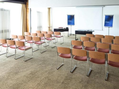 a room with rows of chairs and a podium at Novotel Macon Nord - Porte de Bourgogne in Mâcon