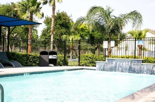 a swimming pool with a fountain in front of a fence at Verta Hotel McAllen Airport in McAllen