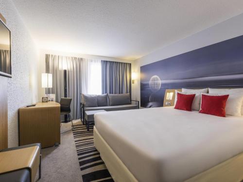 a hotel room with a large bed with red pillows at Novotel Strasbourg Centre Halles in Strasbourg