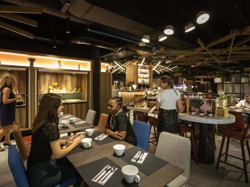 a group of people sitting at tables in a restaurant at Novotel Strasbourg Centre Halles in Strasbourg