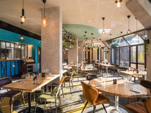 a restaurant with wooden tables and chairs and windows at Novotel Le Mans in Le Mans