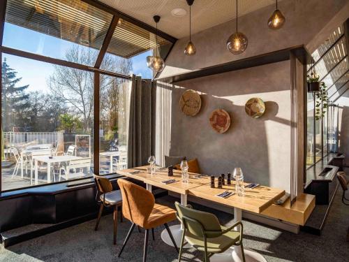 a restaurant with a table and chairs and a large window at Novotel Le Mans in Le Mans