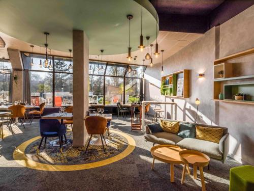 a living room with a couch and tables and chairs at Novotel Le Mans in Le Mans