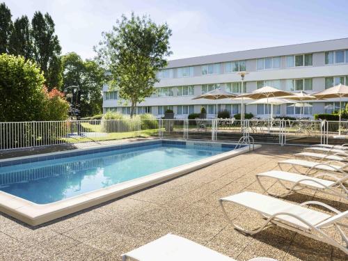 a swimming pool with chairs and a hotel at Novotel Le Mans in Le Mans