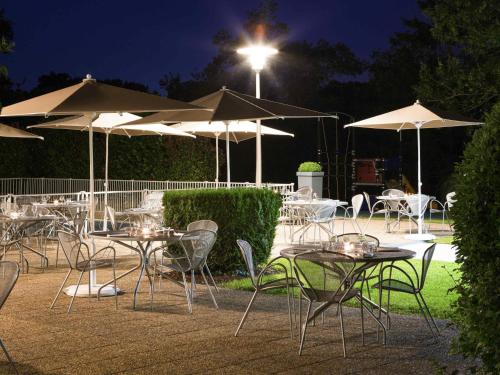 a group of tables and chairs with umbrellas at night at Novotel Le Mans in Le Mans