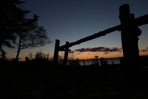 a sunset over the water behind a wooden fence at Auberge La Coudriere (Cool Hotel) in L'Isle-aux-Coudres