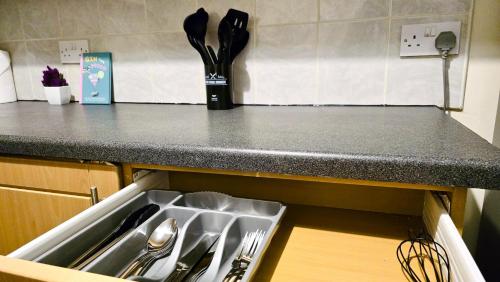 a kitchen counter with a sink and utensils at Comfy Entire Apartment with Free Parking in Bury Town in Bury