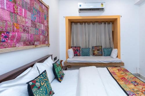 a room with two beds and a window with a couch at Sundar Haveli in Jaisalmer