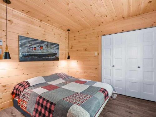 a bedroom with a bed in a wooden cabin at NEW Chalet des pins - lake access in Saint-Alphonse-Rodriguez