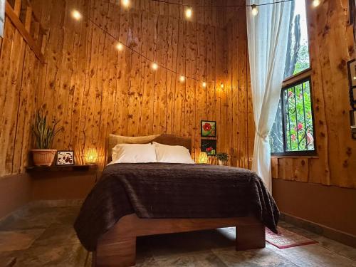 a bedroom with a bed with a wooden wall at Casa Colibri Chirripó in Herradura