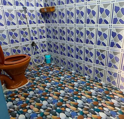 a bathroom with a toilet and a tiled floor at BlueWaves in Pondicherry