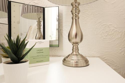 a lamp sitting on a table next to a plant at Spacious 3 Bedroom Home In The Heart Of Port Talbot By EKLIVING - Short Lets & Serviced Accommodation in Port Talbot