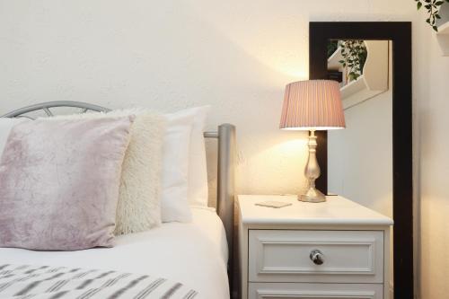 a bed with a nightstand with a lamp and a mirror at Spacious 3 Bedroom Home In The Heart Of Port Talbot By EKLIVING - Short Lets & Serviced Accommodation in Port Talbot
