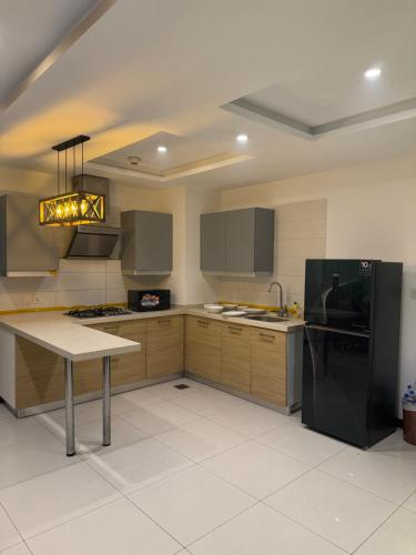 a kitchen with wooden cabinets and a black refrigerator at Elan Spaces 1BHK in Rawalpindi
