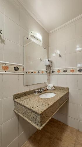 une salle de bain avec un lavabo et un miroir dans l'établissement Pousada Vilage Inn Capivari Campos do Jordão, à Campos do Jordão