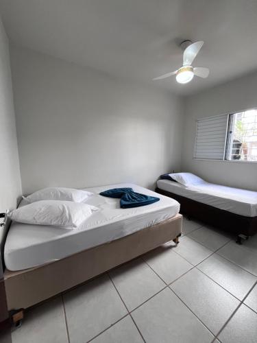 two beds in a bedroom with a ceiling fan at home select apto inteiro 2 quartos Araguari in Araguari