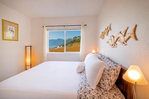 una camera da letto con un letto bianco e una finestra di Magnificent Oceanview by OceanviewHotTubs Oceanfront! Shelter Cove, CA Tesla EV station a Shelter Cove