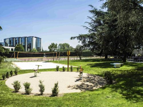 a park with a volley ball court in the grass at Novotel Toulouse Purpan Aéroport in Toulouse