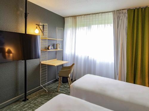 Una habitación de hotel con dos camas, un escritorio y una ventana. en Novotel Metz Amnéville, en Maizières-lès-Metz
