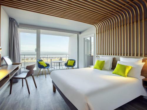 a bedroom with a large bed and a large window at Novotel Thalassa Le Touquet in Le Touquet-Paris-Plage