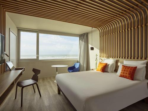 a hotel room with a large bed and a large window at Novotel Thalassa Le Touquet in Le Touquet-Paris-Plage