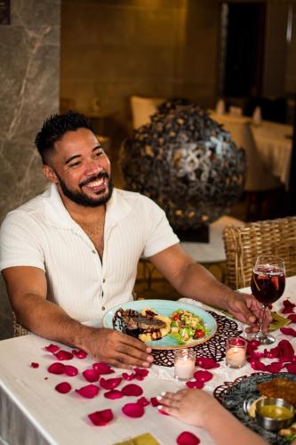 a man sitting at a table with a plate of food at Mantra Hotel Boutique in Santa Marta