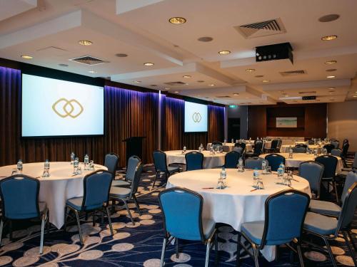 a conference room with tables and chairs and a screen at Sofitel Gold Coast Broadbeach in Gold Coast