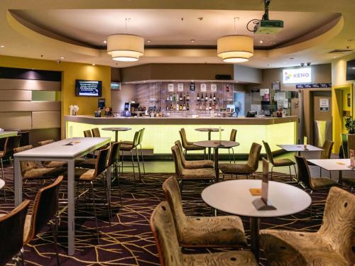 a restaurant with tables and chairs and a bar at Sofitel Gold Coast Broadbeach in Gold Coast