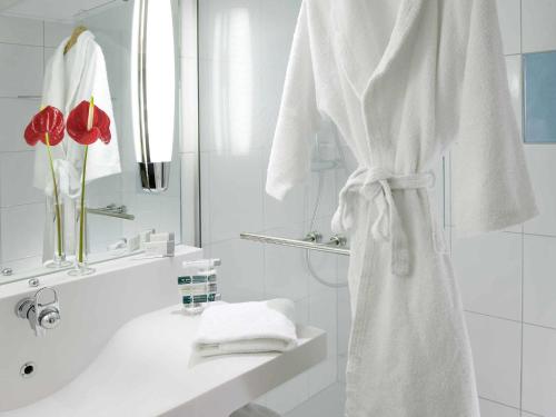a white bathroom with a sink and a towel at Novotel Roissy Saint Witz in Saint-Witz
