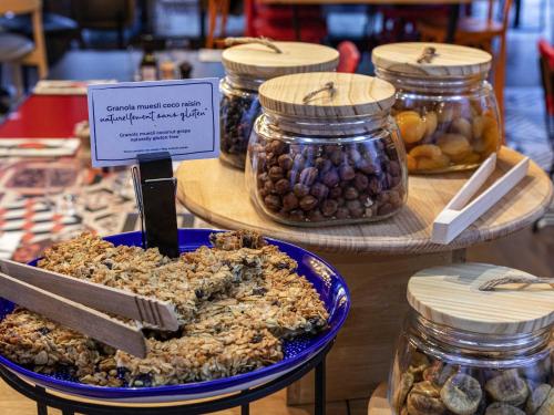 a display of jars of nuts and olives on a table at Novotel Roissy Saint Witz in Saint-Witz