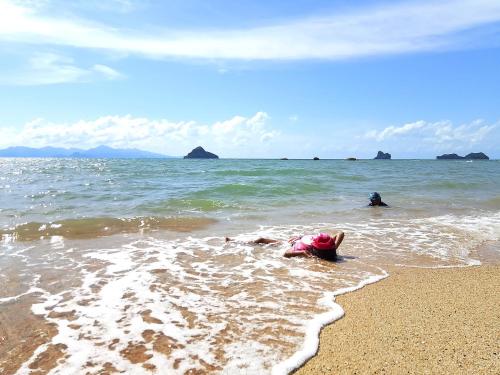 a person laying in the water at the beach at Aura Bluewave Beach House and Mini Beach Cafe in Tanjung Rhu 