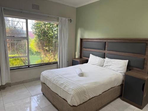 a bedroom with a large bed with a large window at Horizon Bed and Breakfast in Roodepoort