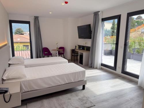 a bedroom with two beds and a desk and a television at Lake & More Suite Hotel in Paratico